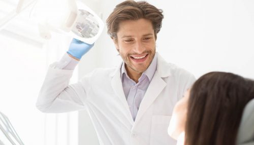 Cheerful young dentist greeting his female patient